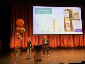 En kvinna och en man talar på en scen.