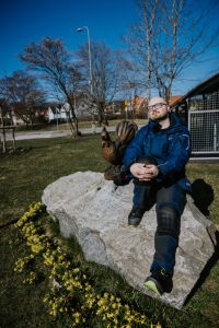 En fastighetsvärd sitter på en sten i Kyrkbyn och solar sig.