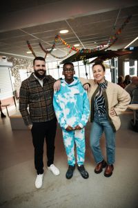 En pojke i mitten med en vuxen man på vänster sida och en vuxen kvinna på höger sida tittar in i kameran.