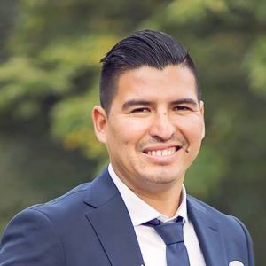 Närbild på man i kostym som ler. 