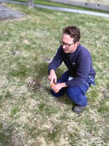 En man sitter på huk på gräset.