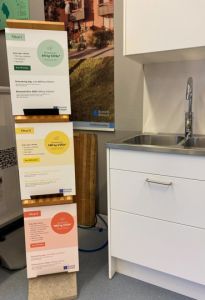 Tre skyltar i olika färger bredvid en diskbänk.