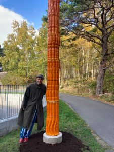 En man står bredvid en orange kolumn.