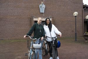 Två kvinnor som står bredvid varandra med sina cyklar.