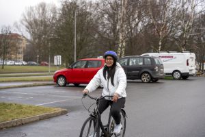 Kvinna på cykel på en parkeringsplats.