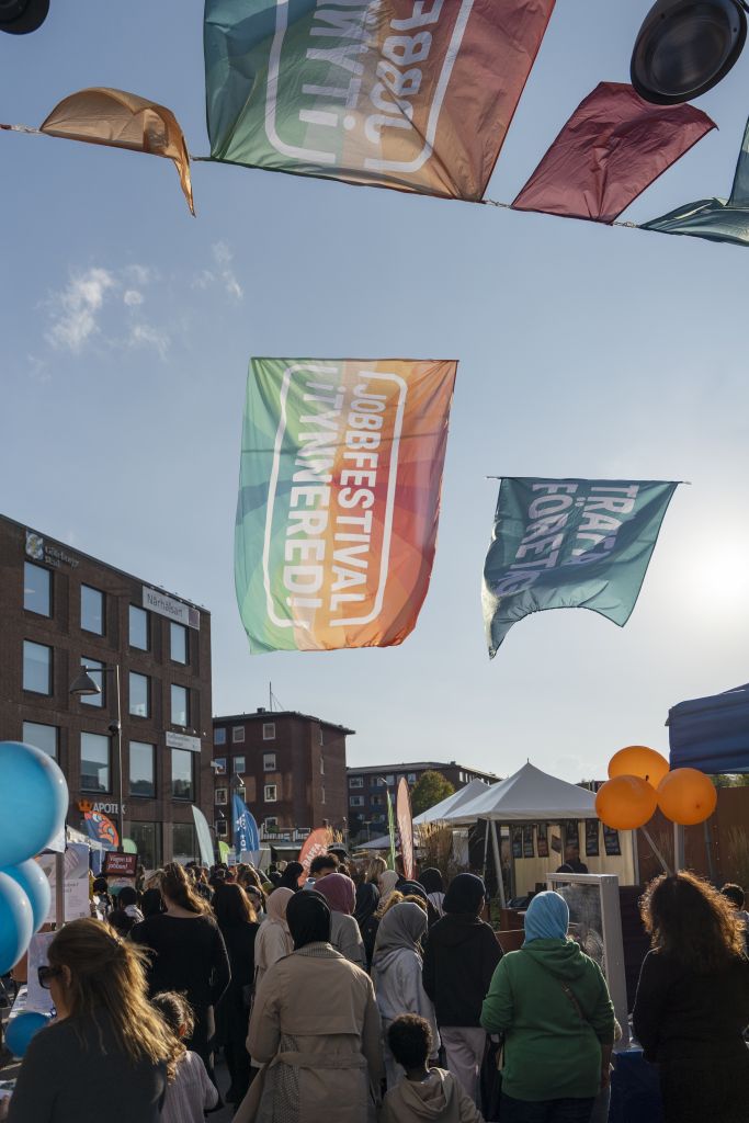 Ryggarna av folkmassa med flaggor och blå himmel.