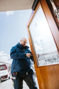 En man fixar med ett lås till en dörr.