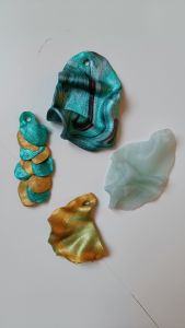 Pysslade färgglada drakfjäll som ska hänga i en mobil.