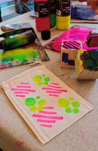 Färgglatt tygtryck på ett bord med färgflaskor i bakgrunden.