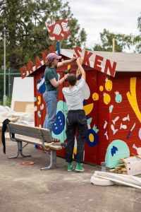 Två ungdomar målar en liten stuga.