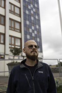 En man i blå arbetskläder tittar bort i fjärran.