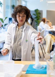 En pojke i vit labbrock känner på kvävegas som bildats. 