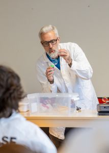 En man i vit labbrock blåser såpbubblor. 