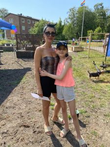 Två glada hyresgäster, mamma och dotter, vid odlingsområdet.