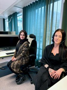 Två kvinnor tittar in i kameran och ler.