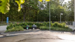 Två sopbehållare med grönt i bakgrunden.