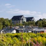 I förgrunden syns fritidsstugor och i bakgrunden syns höga hus.