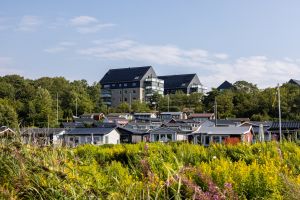 I förgrunden syns fritidsstugor och i bakgrunden syns höga hus.