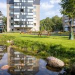 Ett högt hus med en damm i förgrunden.