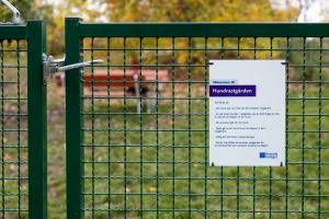 En grind med skylt på som välkomnar in till hundrastgården.