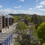 Utsikten från högsta våningen. Hustak och skog i solljus.