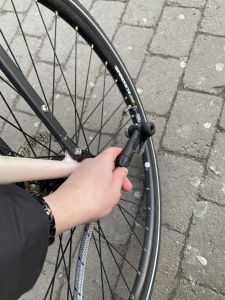 Foto på en hand som håller i en cykelpumpsslang och ska pumpa ett däck. 