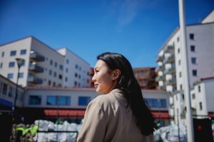 Kvinna sedd i profil med nyproducerade hus i bakgrunden.