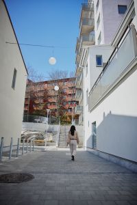 En kvinna går iväg från kameran. Hyreshus runt omkring.