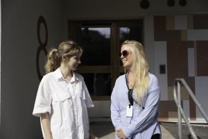 Två kvinnor ler mot varandra i solskenet.