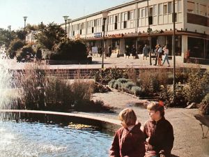 Bild från 50-talet från Kortedala Torg. Två flickor sitter längst fram i bild och tittar i fontänen.