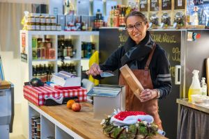En kvinna mäter upp kaffe i en påse och tittar in i kameran.