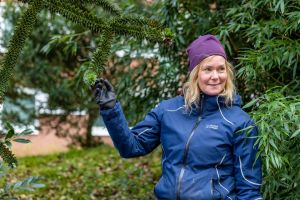 En kvinna klädd i arbetskläder håller i en kvist.