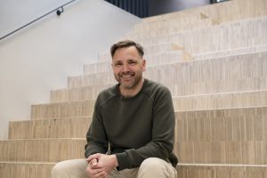 En man sitter och ler i en trappa.