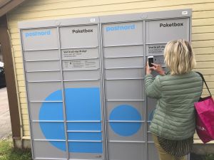 Bilden föreställer postboxar och en kvinna som står framför med ryggen mot kameran.