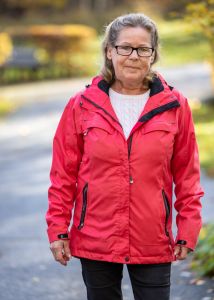 En kvinna i röd jacka som tittar in i kameran.