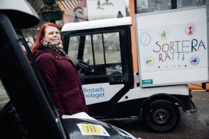 En kvinna står framför en av Bostadsbolagets bilar och ler mot kameran.