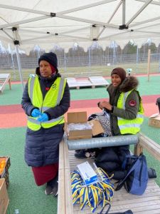 Två kvinnor i funktionärsväst tittar in i kameran och ler.