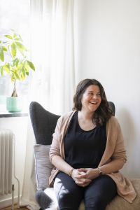 En kvinna som sitter i en stol och tittar åt sidan.