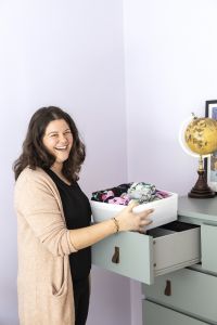 En kvinna håller i en låda med kläder och skrattar.