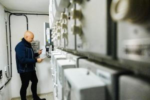 En man står i ett kontrollrum och tittar på elmätare.