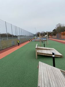 En idrottsbana och i bakgrunden springer små barn på löparbanan.