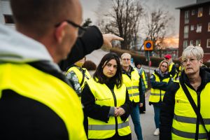 En grupp i varselvästar lyssnar på polisen.