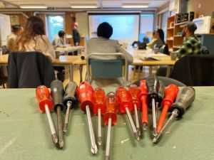 Skruvmejslar i förgrunden och ryggar på människor i bakgrunden.