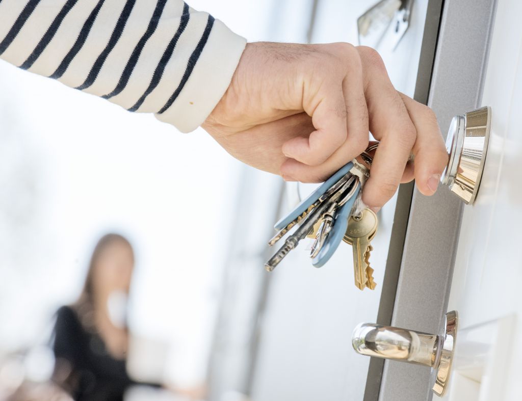 Bilden visar en hand som sätter in nycklar i ett lås