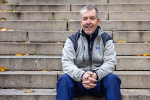 En man sitter på en trappa och ler mot kameran.