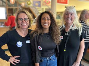 Tre kvinnor står bredvid varandra och ler in i kameran.