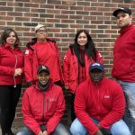 Gruppbild på sex trygghetsvärdar i röda jackor. Tre kvinnor och tre män. Alla män bär keps.