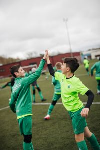 Två pojkar i fotbollskläder gör en high five.