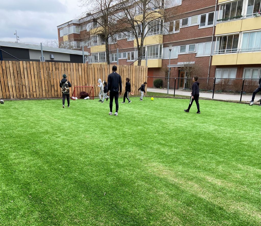 Barn som spelar fotboll på en konstgräsplan. 