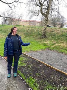 En kvinna i arbetskläder pekar på ett naturområde